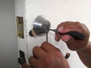 Carpenter fixing a lock in the door with a screwdriver
